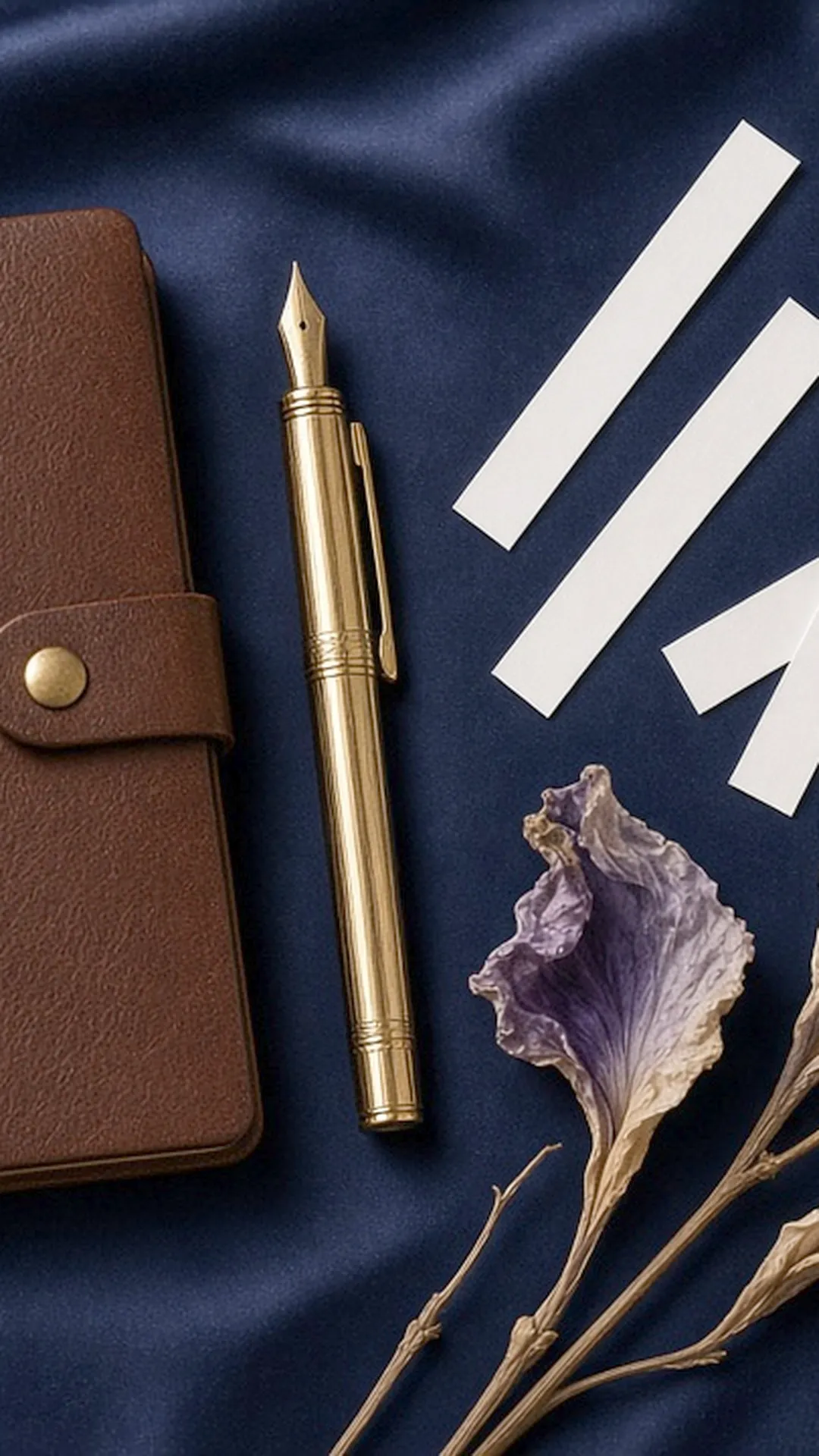 Notebook, pen, paper blotters, and a dried iris on navy fabric